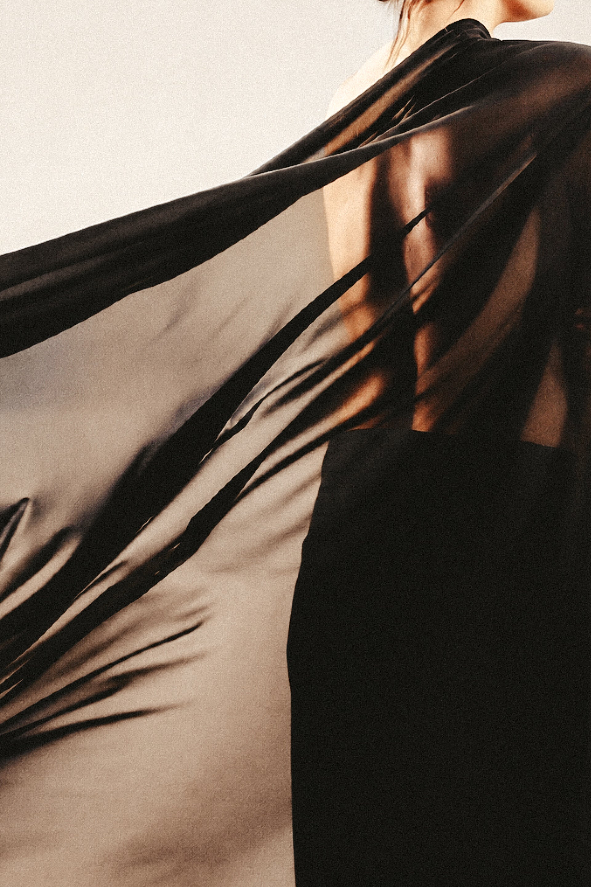 Black fabric draped over a person against a neutral background