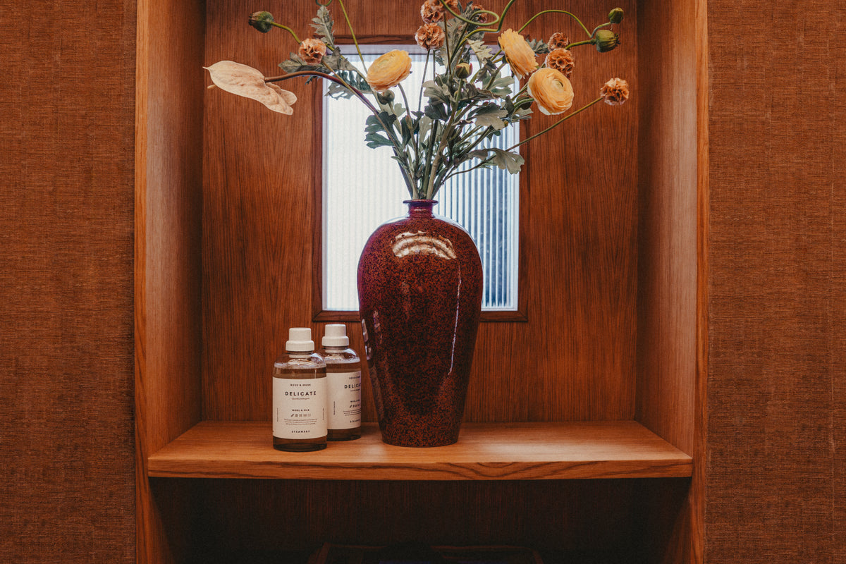 2 detergent bottles on a shelf next to flower vase