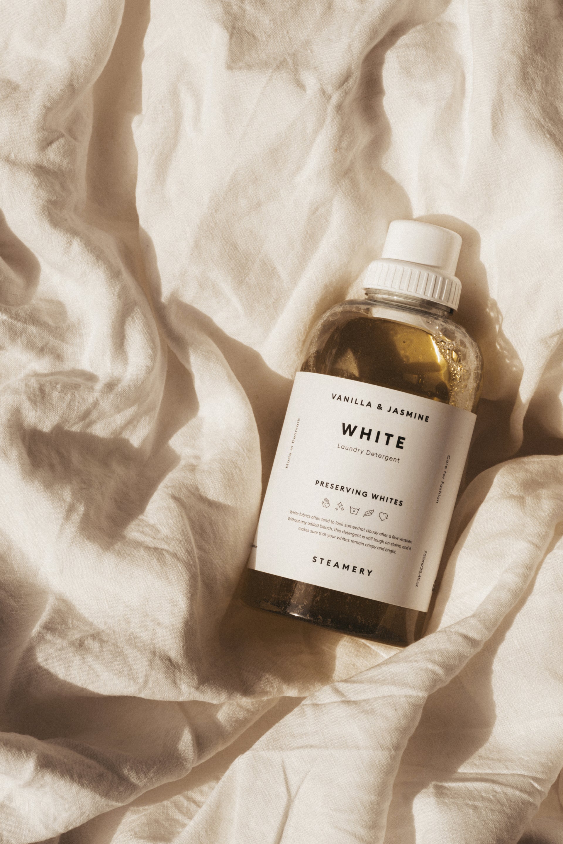 Bottle of 'White' laundry detergent on a textured fabric background