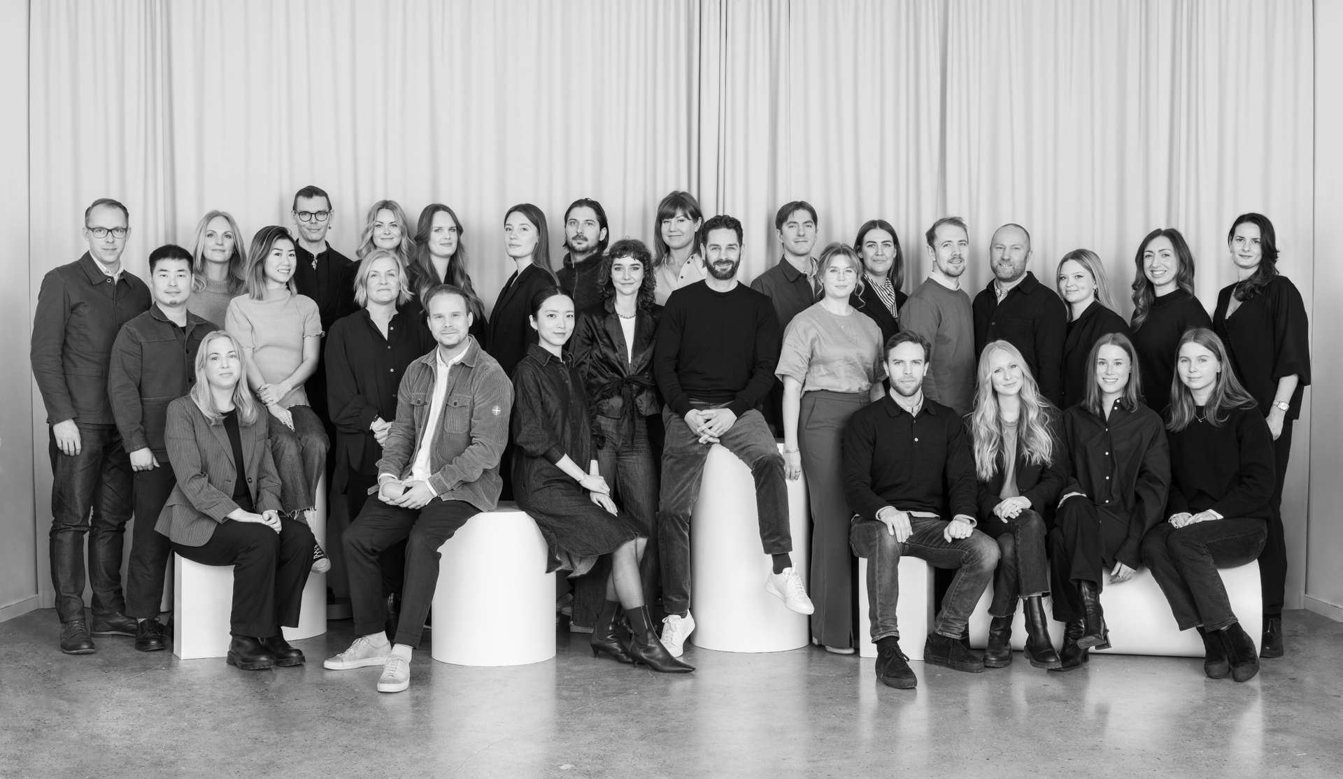 Black and white group photo of a large team in a modern office setting.