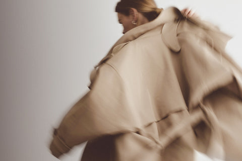 Close-up of a woman wearing a beige coat with a blurred background