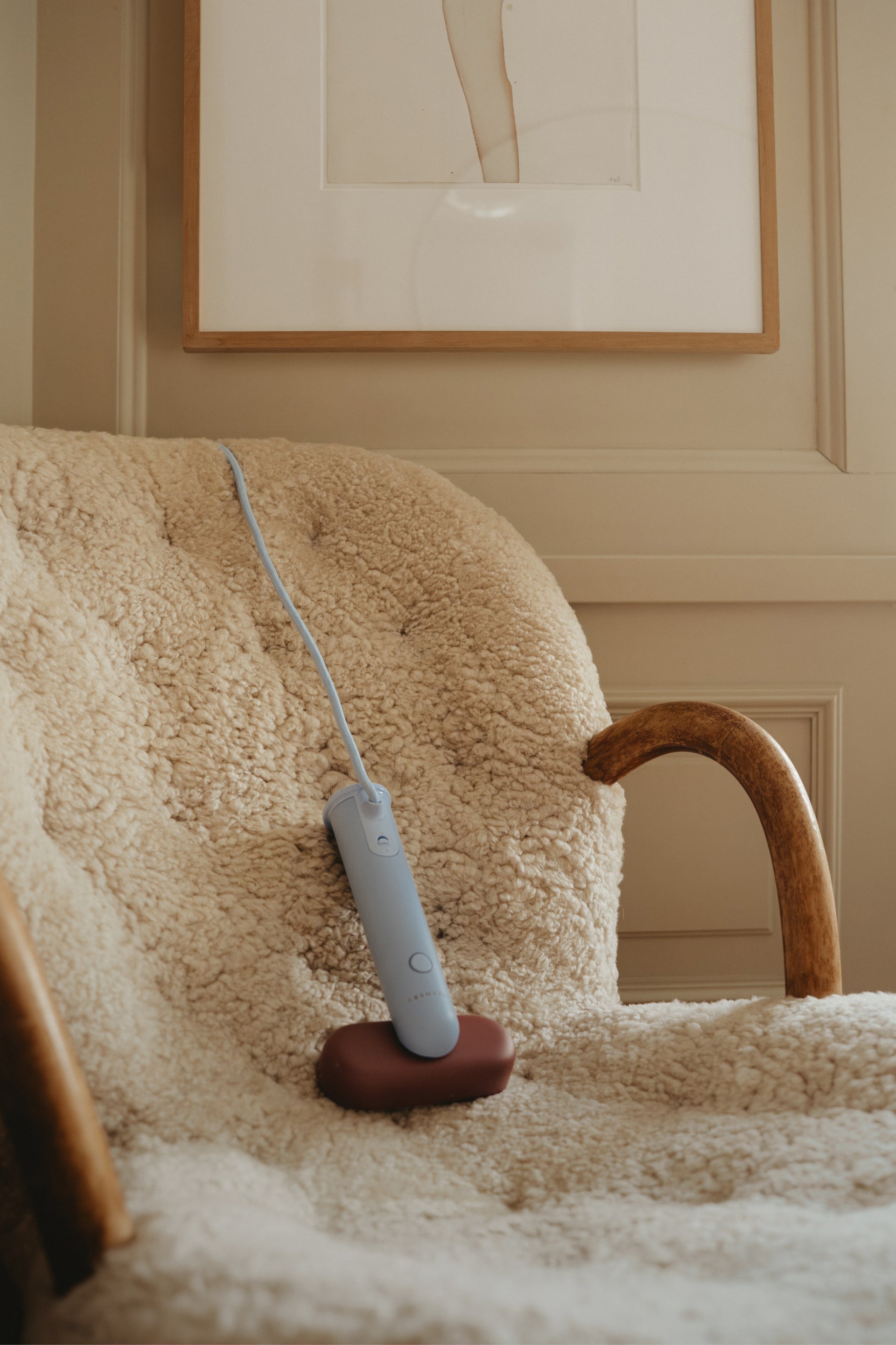 Handheld travel steamer on a fluffy chair with a framed picture in the background