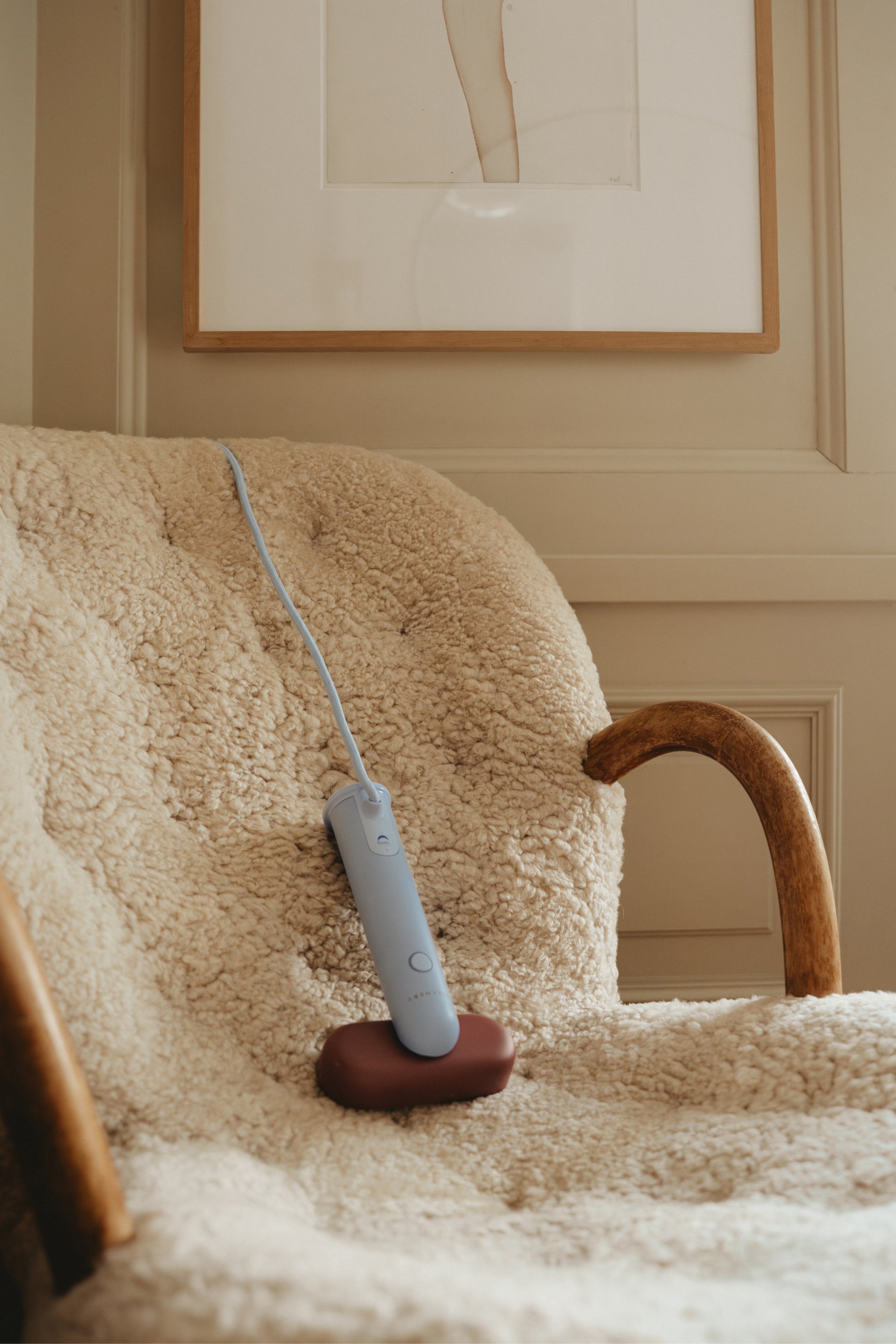 Handheld travel steamer on a fluffy chair with a framed picture in the background