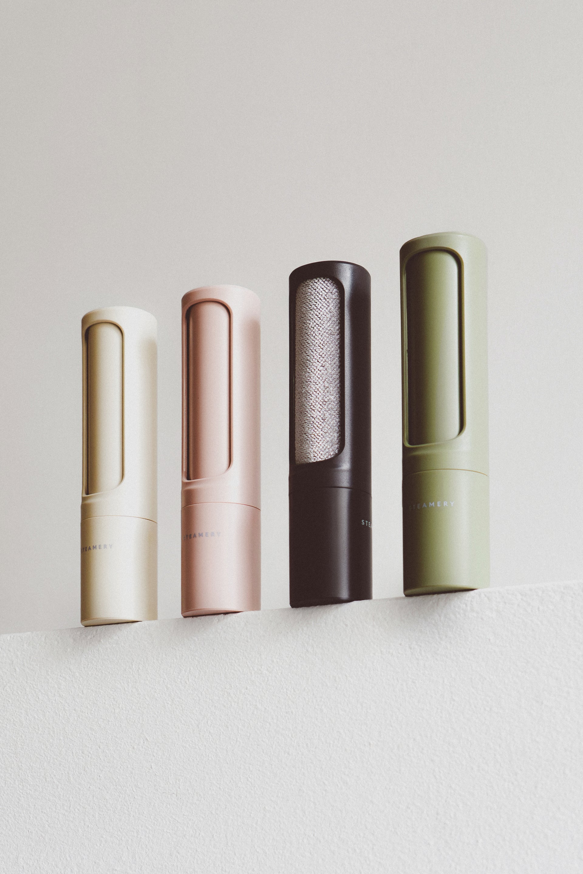 Four lint brushes in different colors on a light gray background