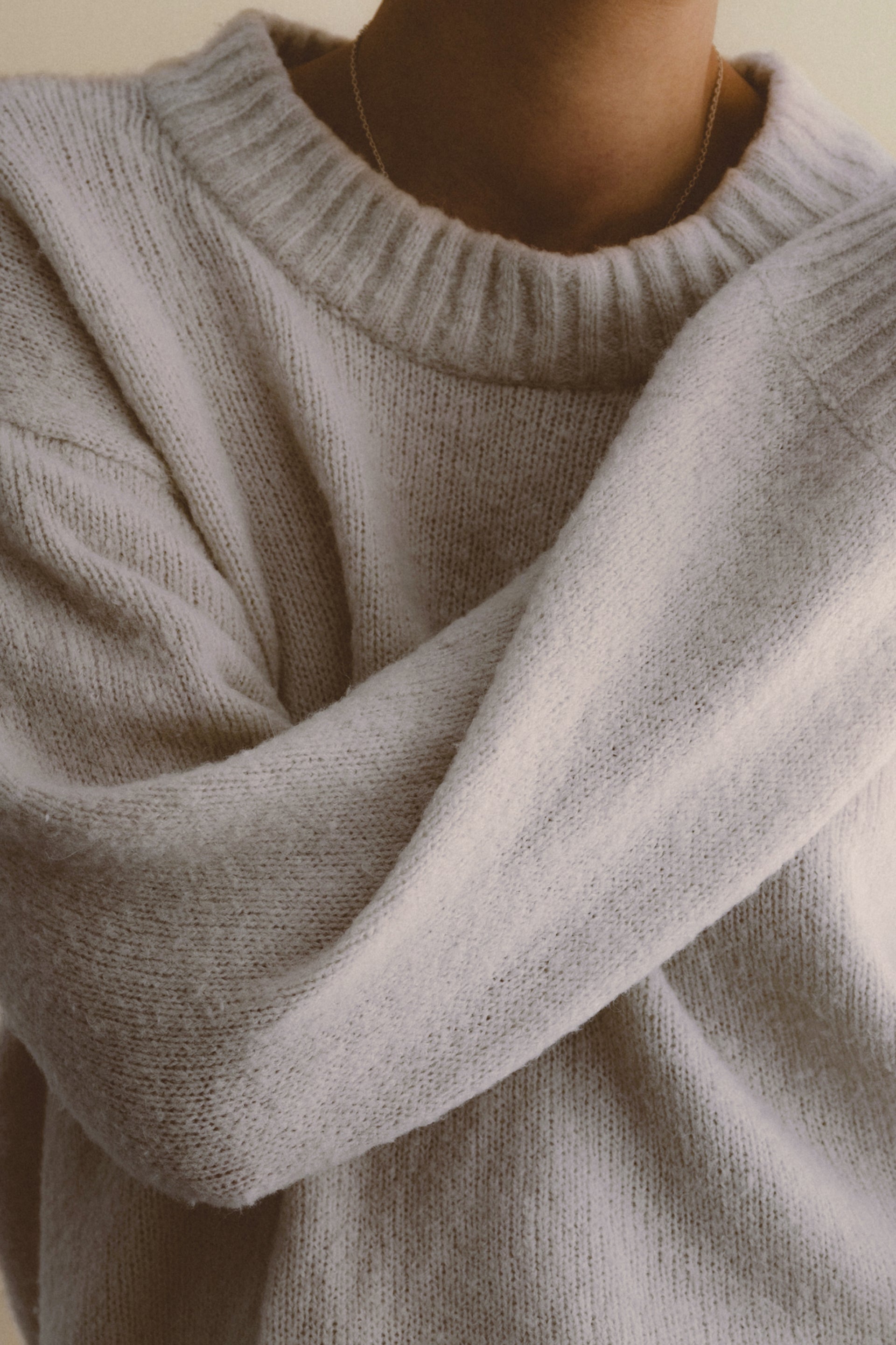 Close-up of a person wearing a light blue sweater with a neutral background