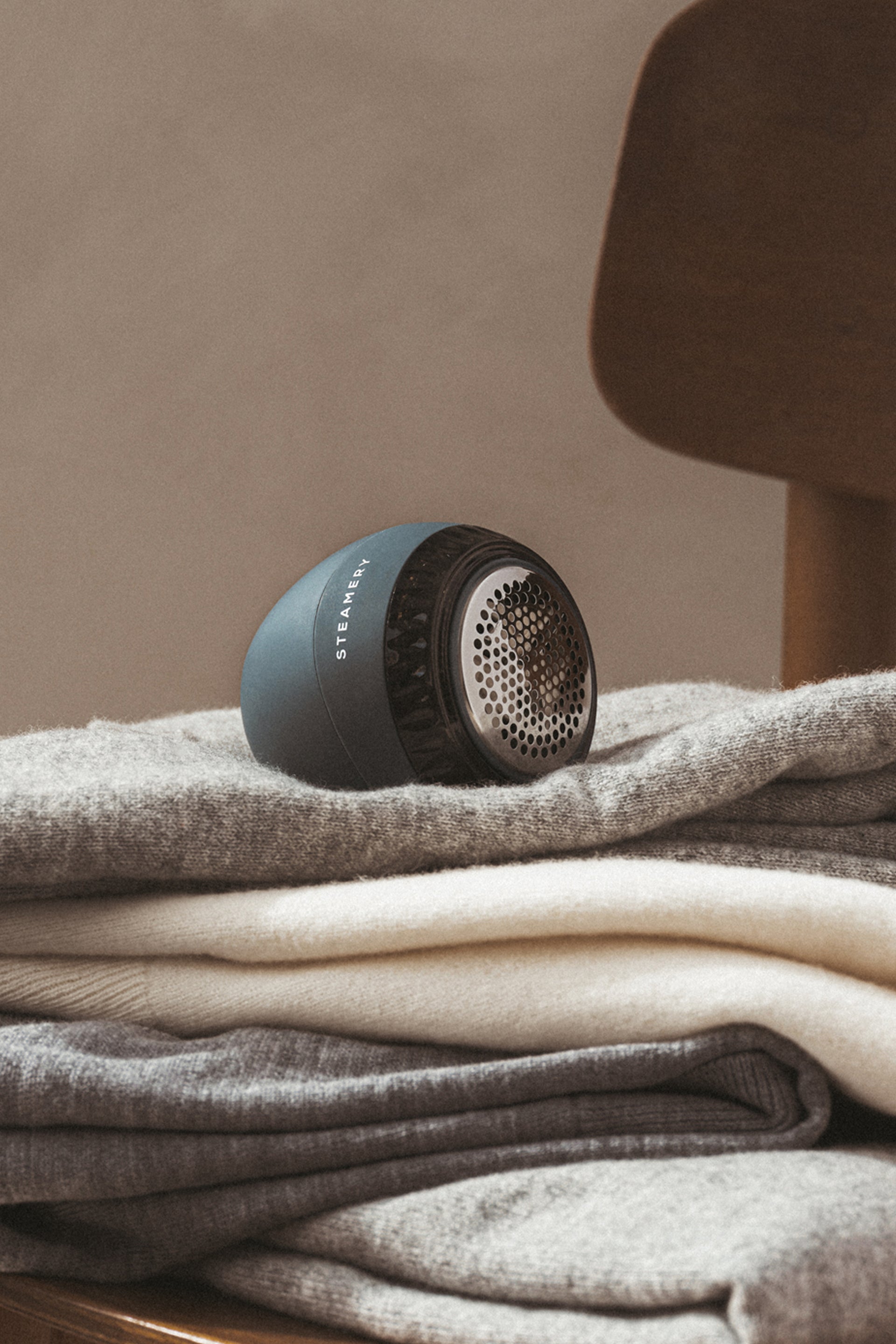 Blue fabric shaver on a pile of garments on a chair