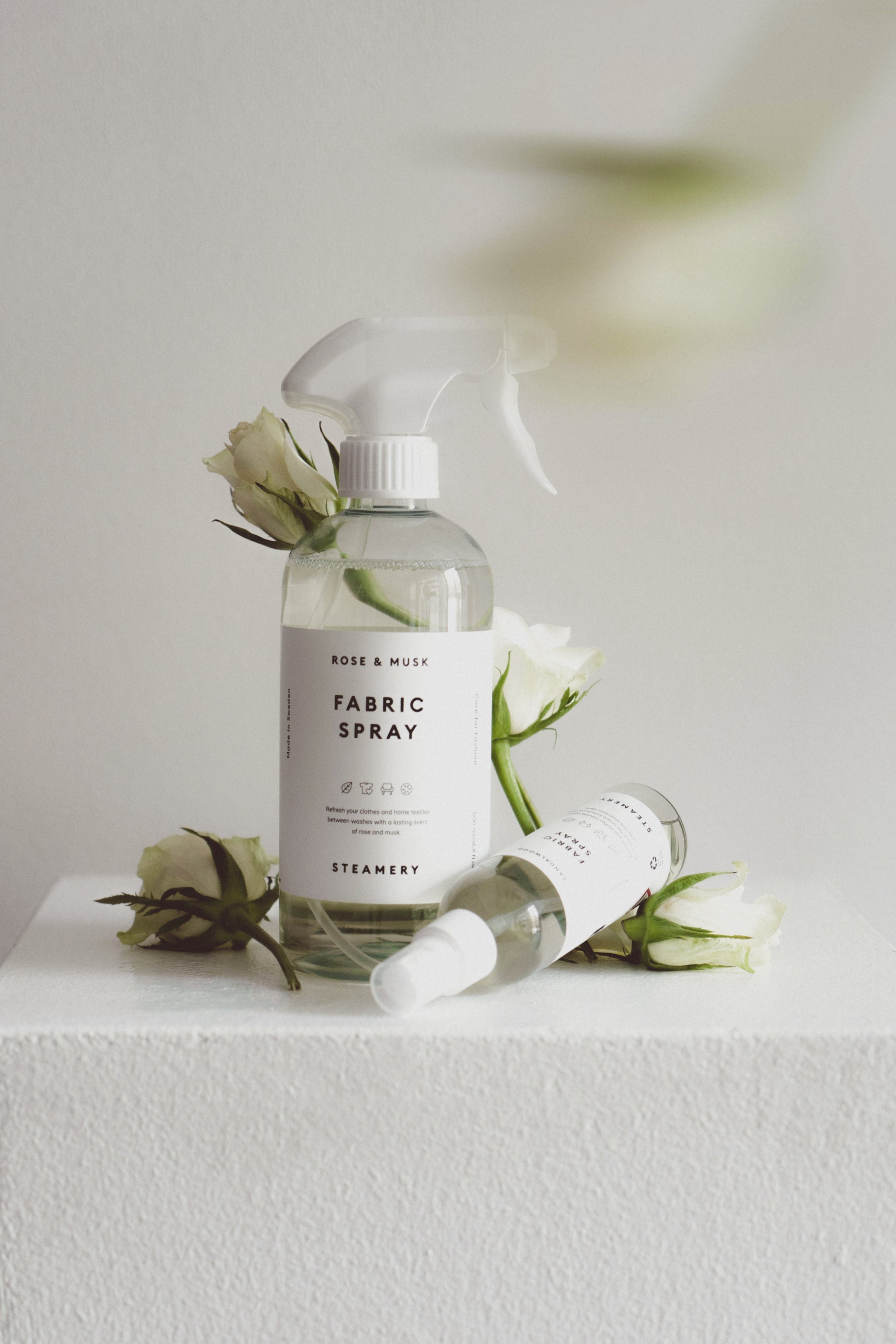 Fabric spray bottle with flowers on a white surface and background
