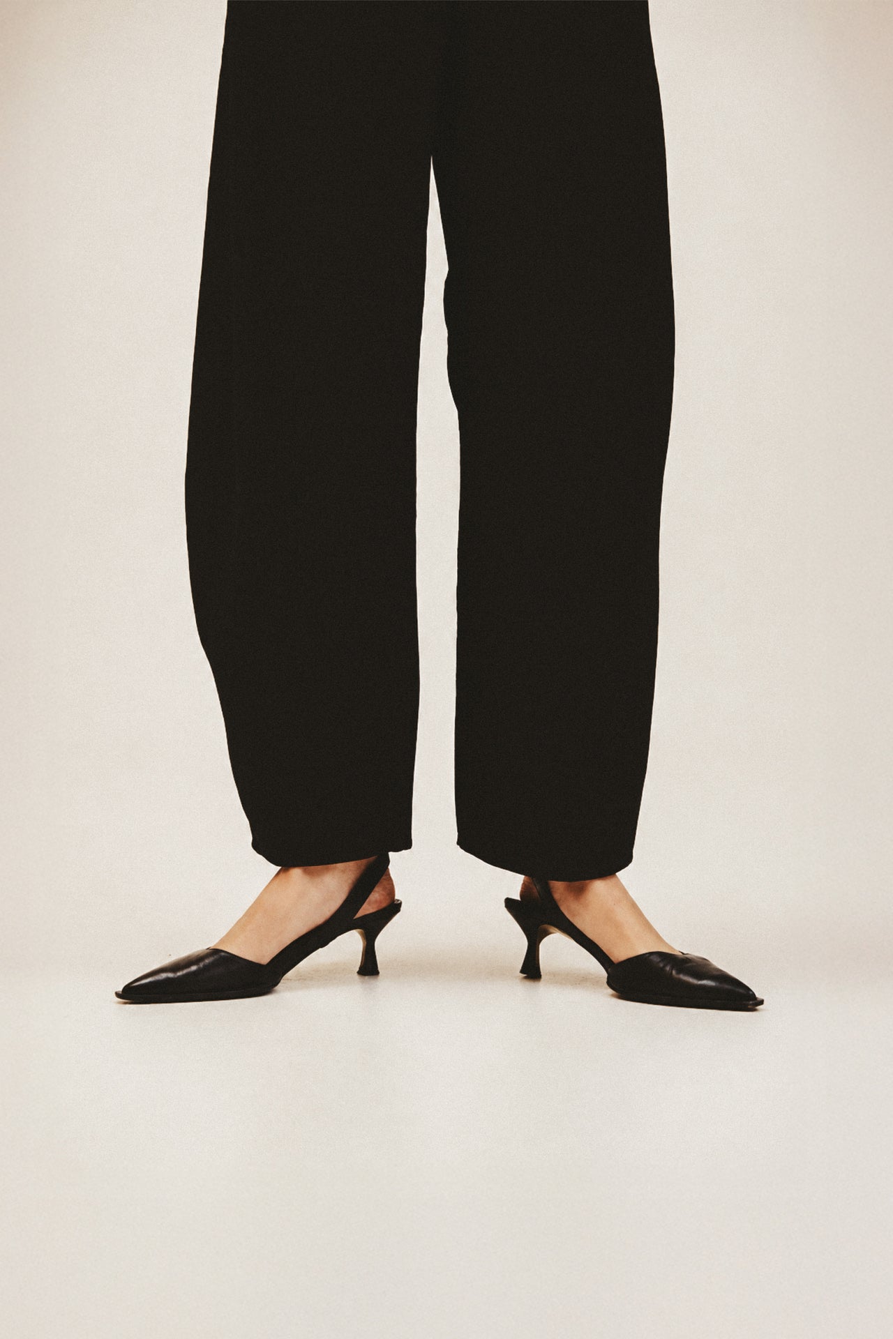 Person wearing black pants and black shoes on a white background