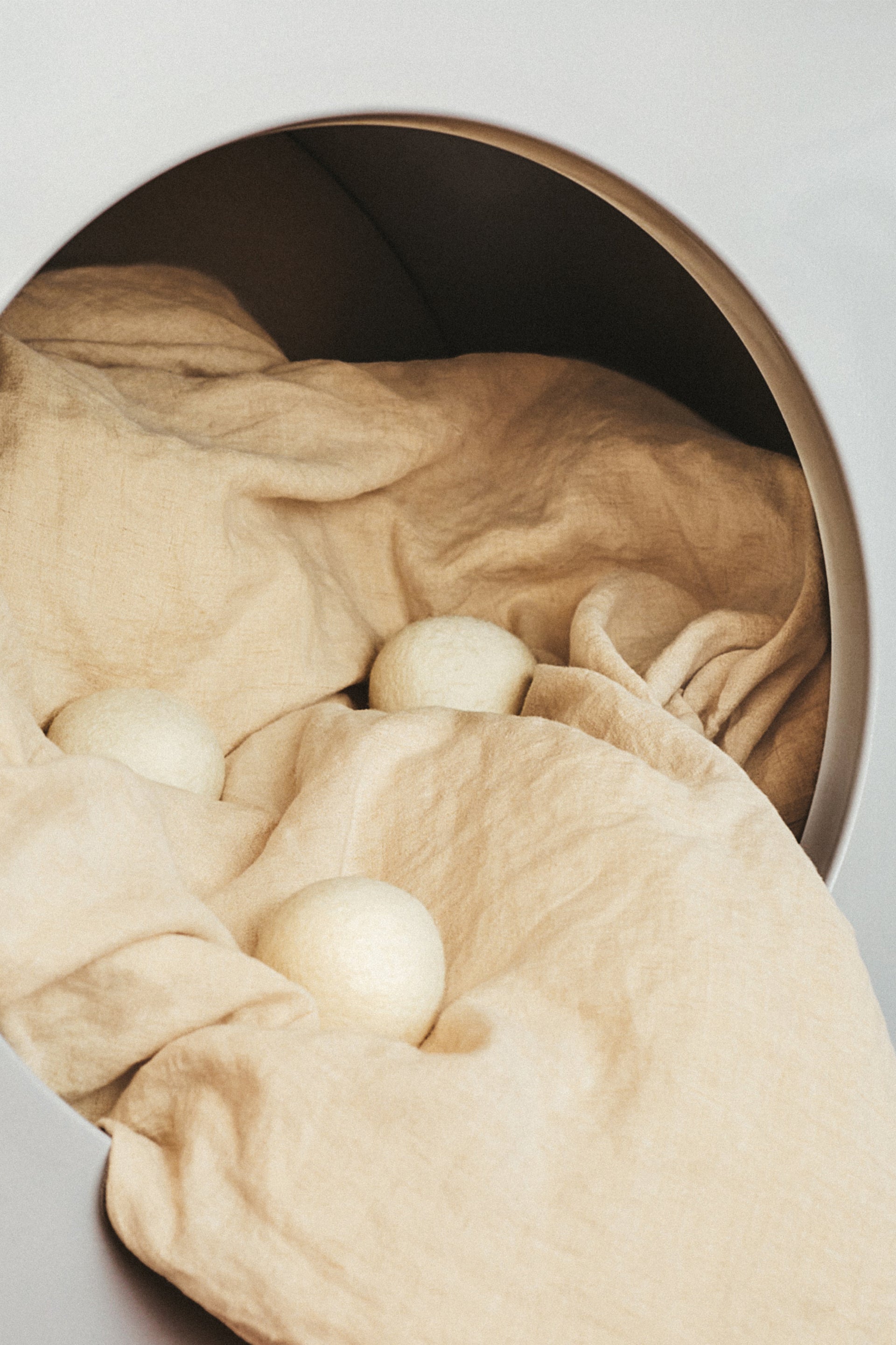 Beige fabric with white tumble balls inside a dryer drum