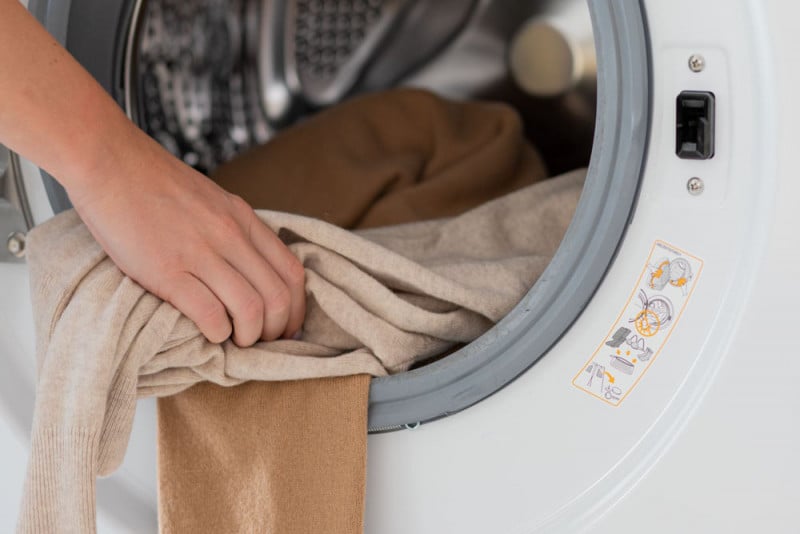 A person loading wool garments into a washing machine